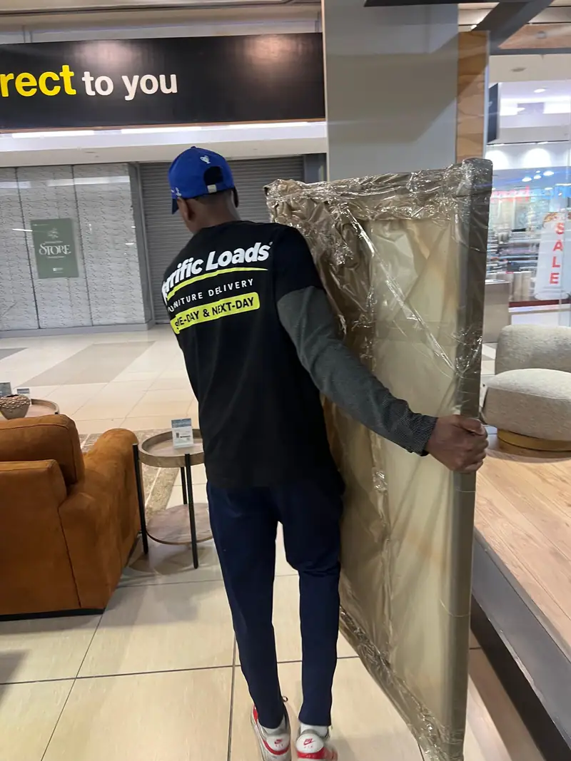 Team member carrying a wrapped décor piece through a furniture showroom